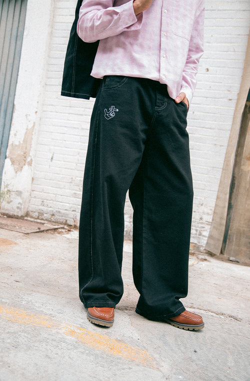 Pantalón unisex de denim negro con ilustraciones bordadas.