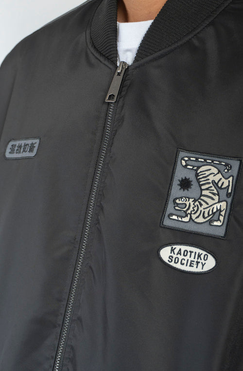 Chaqueta bomber negra Asakusa con parches bordados y gráfico de tigre de inspiración japonesa en la espalda.