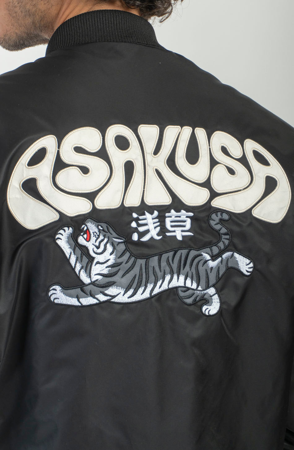 Chaqueta bomber negra Asakusa con parches bordados y gráfico de tigre de inspiración japonesa en la espalda.