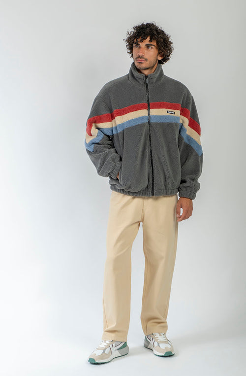 Polar Wabi Sabi Khaki de fleece con franjas rojas, beige y azules, cuello alto y cierre de cremallera.